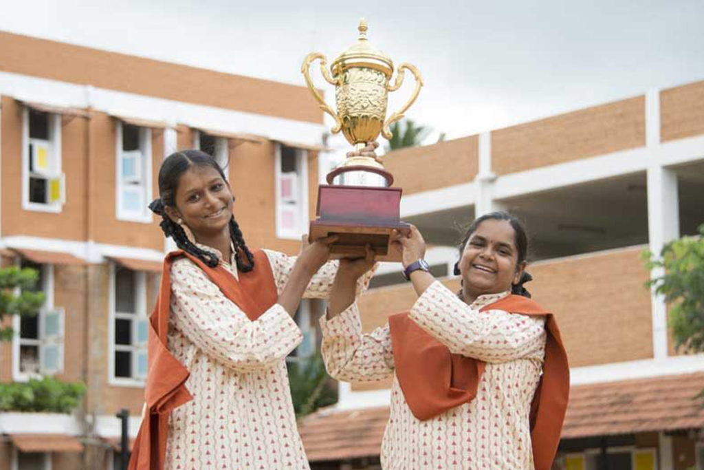 Two smiling women hold a trophy