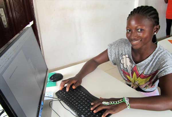 A young woman smiles while using a computer